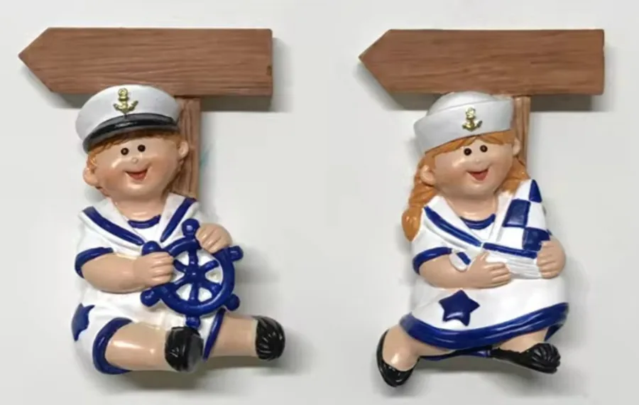 Pair of resin souvenir magnets of sailor children holding blank wooden signposts for destination text.