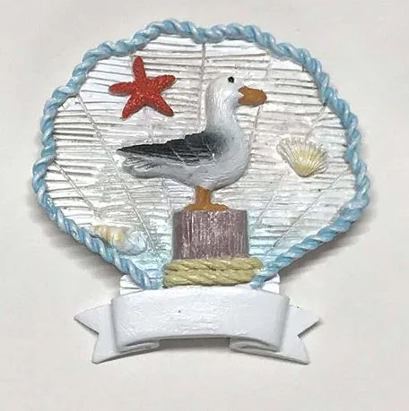 Scallop-shell resin souvenir magnet with a seagull on a mooring post and a blank ribbon banner.