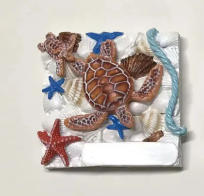 Resin souvenir magnet tile of sea turtles, starfish and shells with a blank name plate.