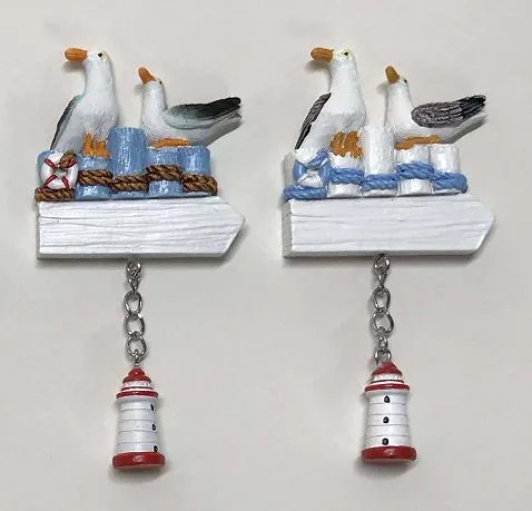 Resin souvenir magnet of seagulls on a jetty with a hanging lighthouse charm, shown in two colourways.