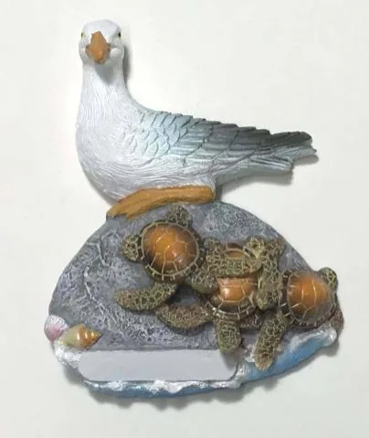 Resin souvenir magnet of a seagull and turtles on a shell-shaped rock with a blank name plate.