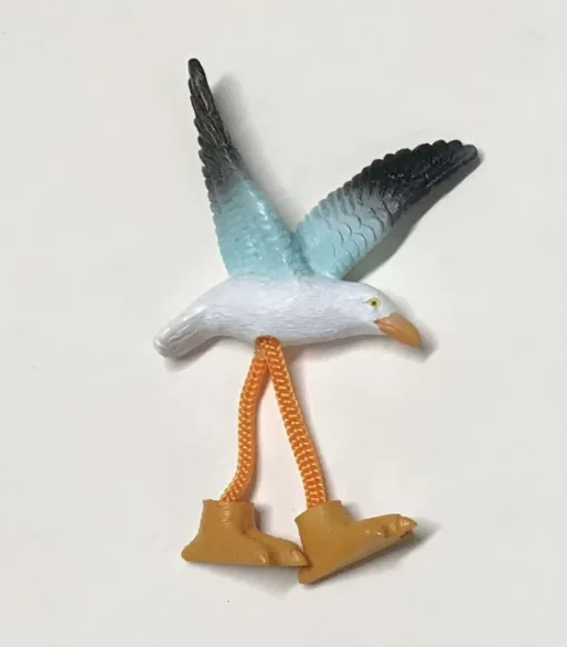 Resin souvenir magnet of a seagull with wings raised and dangling rope legs.
