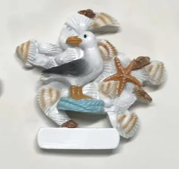 Resin souvenir magnet of seagulls among shells and starfish with a blank name plate.
